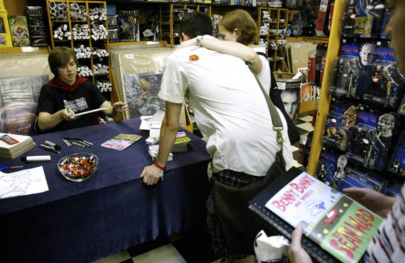 肖恩·沃德(Sean Ward)在The Silver Snail/>书店向他的粉丝们打招呼。沃德周围环绕着一堆硬纸板，还有大约六只可以签名和素描的记号笔。